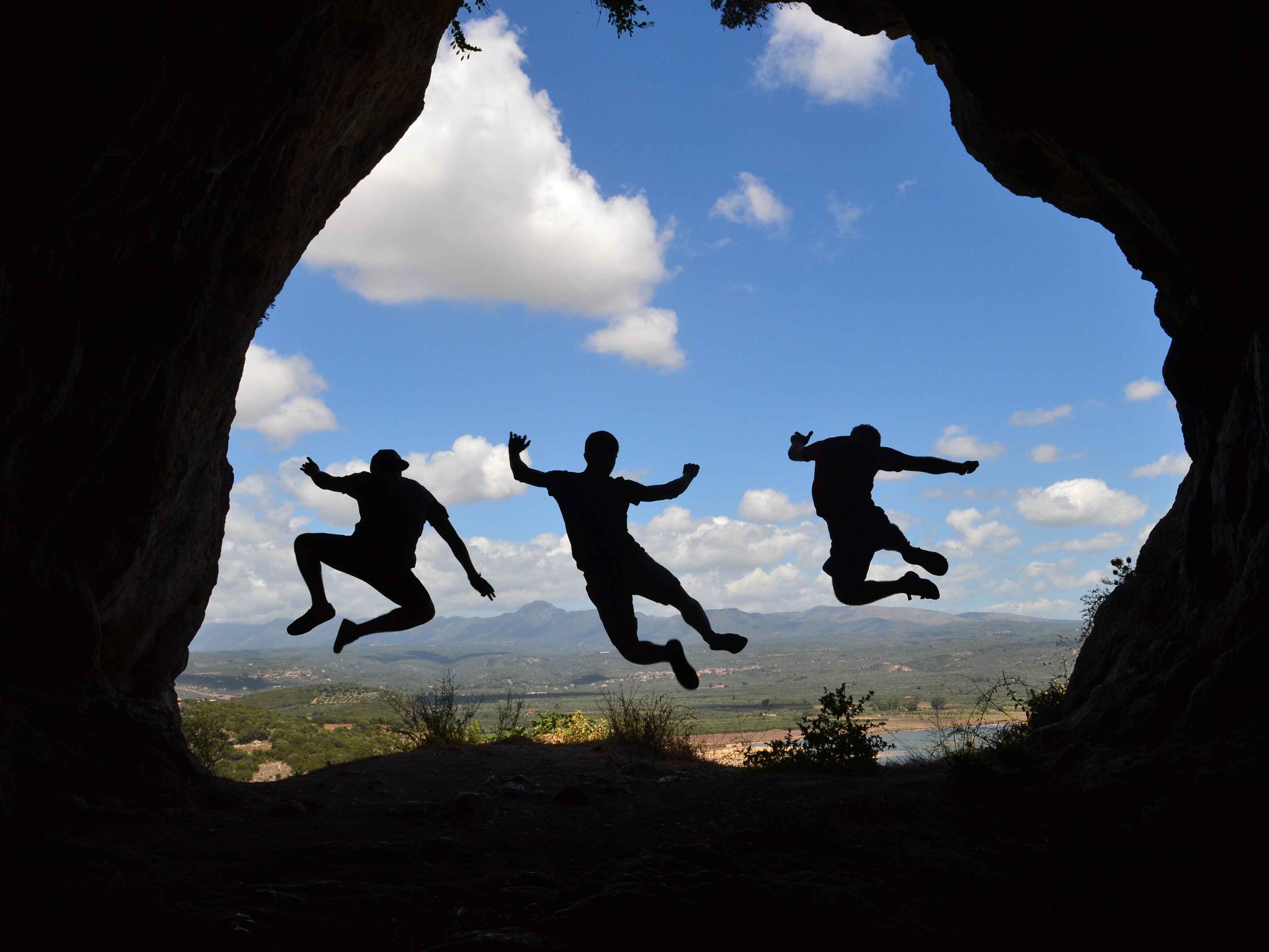 Drei junge Personen springen im Naturpark gleichzeitig in die Luft.